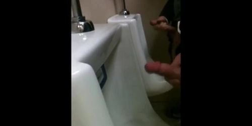 two slim dicks getting wanked at the urinals