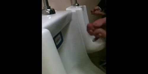 two slim dicks getting wanked at the urinals